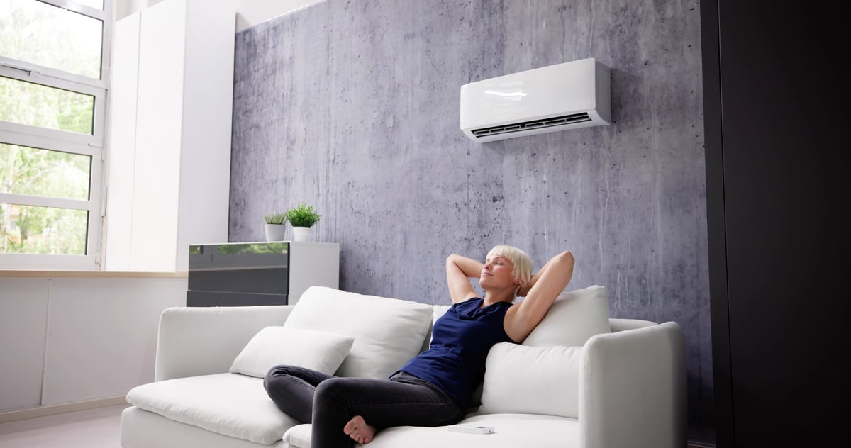 Happy Young Woman Relaxing Under The Air Conditioner